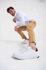 Zapatillas urbanas blancas de cuero sintético con cordones y detalle negro en el talón.