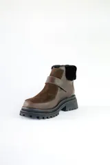 Bota corta de cuero marrón con puntera de gamuza, cuello de piel sintética negra, cierre con velcro y suela track negra.