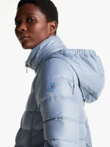 Campera celeste acolchada con relleno de plumón, cuello chimenea y capucha plegable. Cuenta con cierre de cremallera, bolsillos laterales con cremallera y puños elásticos con botones a presión.