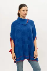 Capa tipo poncho tejido de punto color azul con detalles en rojo.