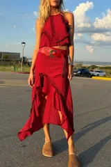 Conjunto de dos piezas compuesto por un top sin mangas con cuello alto y una falda midi asimétrica con volados, ambos confeccionados en seda con textura arrugada.