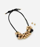 Conjunto de bijouterie compuesto por un collar con cordón negro ajustable y dije de esferas en tonos dorado y negro, acompañado por un par de aros tipo botón en tono dorado.