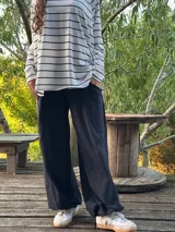 Remerón de manga larga, color blanco con rayas horizontales negras, corte oversize con tajos laterales y bajo redondeado.