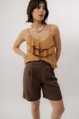 Musculosa negra con escote en V, breteles finos regulables y doble volado frontal con pespuntes.