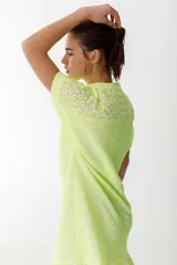 Vestido amarillo neón con textura arrugada, corte recto, largo hasta la rodilla, manga corta y cuello mao con abertura en V.