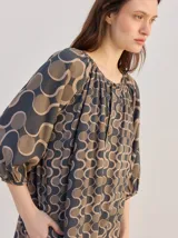 Vestido midi de diseño suelto con estampado geométrico en tonos marrones y beige, mangas 3/4 y cuello mao.