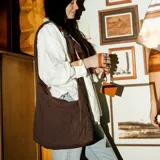 Bolso tipo hobo o slouchy de material acolchado color marrón oscuro, con costuras en patrón de rombos. Posee un bolsillo exterior frontal y correa de hombro ancha y ajustable.