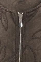 Chaqueta bomber color marrón con cuello redondo, manga larga con puño elástico y cierre frontal de cremallera metálica. Presenta un diseño de bordados florales en relieve por toda la prenda y bolsillos delanteros de vivo.