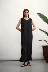 Vestido largo negro sin mangas, de corte recto y holgado, con costuras blancas visibles en el centro del frente y alrededor del cuello.