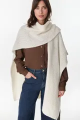 Ruana de punto color crudo, de diseño amplio y envolvente con textura de tejido abierto.