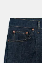 Jeans de tiro medio con corte cropped flare, confeccionados en denim azul oscuro. Presentan diseño de cinco bolsillos, trabillas en la cintura, raya planchada en el delantero y bajo con acabado evasé. Cierre frontal con cremallera y botón metálico.