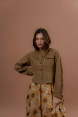 Chaqueta verde militar de corte clásico, cuello mao y cierre frontal con botones. Cuenta con bolsillos ojal en el pecho y mangas largas.