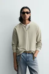 Camiseta de manga larga para hombre con corte relajado, confeccionada en tejido con estructura waffle. Presenta un cuello redondo tipo panadero con cierre frontal de botones a presión.