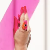 Anillo con base transparente y aplique geométrico en acrílico color rosa, naranja y negro.