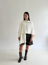 Ruana de tejido de punto trenzado en color crudo, con diseño abierto, corte holgado y mangas amplias tipo kimono.