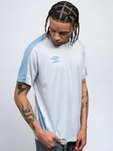 Remera deportiva Umbro de manga corta, color azul marino con detalles en azul claro en los hombros y laterales. Presenta cuello redondo y logo de la marca estampado en el pecho.