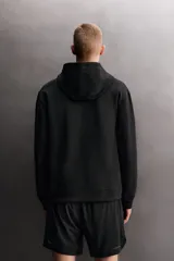 Sudadera de hombre Zara Athleticz de ajuste relajado (relaxed fit), color marrón, confeccionada en tejido técnico compacto con mezcla de algodón y elasticidad. Cuenta con cuello con capucha ajustable con cordones negros, manga larga, bolsillo frontal tipo canguro con un pequeño bolsillo termofijado con cierre, y acabados con rib en puños y cintura.