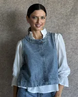 Chaleco de corte recto y largo a la cintura, confeccionado en denim con estampado de rayas verticales en tonos azul y blanco. Presenta cuello redondo y costuras visibles que definen su estructura.