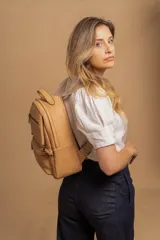 Mochila de cuero sintético color suela, con compartimento principal amplio, bolsillo frontal con cierre y correas ajustables.