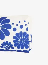 Neceser rectangular de poliéster blanco con estampado de flores y lunares azules. Tiene cierre de cremallera con tirador de cordón y forro interior.