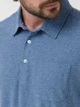 Remera tipo polo de manga corta en color azul jaspeado, con cuello clásico, cierre frontal de dos botones y un bolsillo aplicado en el pecho.