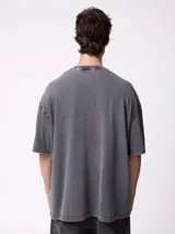 Remera oversize de color gris oscuro con efecto acid wash, mangas cortas y cuello redondo. Cuenta con un pequeño estampado frontal con la inscripción "DIXIE".