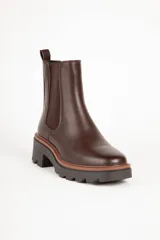 Bota marrón de cuero sintético, estilo Chelsea, con punta redonda, pieza elastizada en los laterales y suela tipo tractor de 6cm de alto.