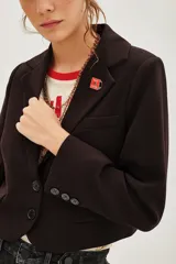 Saco de corte sastre entallado, color negro, con solapas clásicas, cierre frontal de un botón y mangas largas con detalle de botones en los puños.