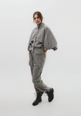 Pantalón de vestir de corte holgado, con pinzas frontales y detalle de solapas decorativas sobre los bolsillos laterales. Presenta cintura de altura media y bolsillos traseros tipo ojal.