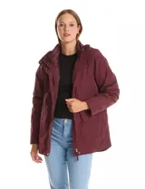 Campera 3 en 1 de color beige, con sistema de capas desmontables. La capa exterior es de tejido técnico resistente al viento y lluvia ligera, con capucha fija, cierre frontal con solapa, bolsillos de parche y ajuste elástico interno en la cintura. Incluye una campera interior capitoneada ultraliviana que puede usarse de forma independiente.