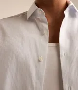 Camisa de manga larga marca Marfinno, confeccionada en tejido dobby de algodón con textura de rayas finas. Presenta cuello inglés y cierre frontal abotonado.