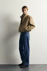 Cazadora regular fit de la colección Aaron Levine x ZARA, confeccionada en tejido con mezcla de algodón con patrón de cuadros pequeños en tonos beige y marrón. Cuenta con cuello subido, manga larga con puño ajustable con botón a presión, bolsillos de vivo en la cadera, bajo ajustable con elástico en los laterales y cierre frontal con cremallera.
