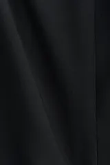 Vestido corto negro sin mangas, con escote redondo, cuerpo entallado y falda acampanada con frunces caídos en la cadera.