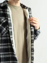 Sobrecamisa de franela a cuadros azul, verde y blanco, con forro de corderito blanco, cuello clásico, cierre frontal con botones, mangas largas y dos bolsillos con solapa abotonada en el pecho.