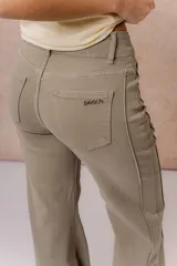 Pantalón de jean color arena con silueta wide leg, tiro medio-alto y costuras verticales delanteras que estilizan la figura. Cuenta con bolsillos funcionales y cierre frontal con doble botón.