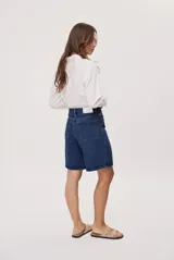 Bermuda de denim azul con calce relajado, tiro medio y largo hasta las rodillas. Cuenta con bolsillos clásicos y trabillas para cinturón.