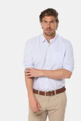 Camisa celeste a rayas verticales, de manga larga con opción de enrollar, corte slim fit, con bolsillo en el pecho y confeccionada en algodón.