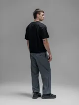 Pantalón cargo de corte oversize confeccionado en microfibra técnica. Presenta cintura elástica, bolsillos laterales y un bolsillo cargo con cierre de broche snap. Incluye un sistema de elásticos con tancas en los tobillos para regular la apertura y la silueta.