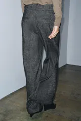 Pantalón de corte recto confeccionado en tejido con mezcla de lana. Presenta tiro medio, cintura con trabillas, bolsillos laterales y traseros, y detalle de nervio frontal. Cierre mediante cremallera, botón y ganchos metálicos.