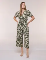 Enterito verde oscuro con estampado floral y abstracto en tono beige, de corte suelto y caída fluida. Presenta escote en V, mangas cortas, cintura elastizada con faja fruncida y pantalón crop de pierna ancha con bolsillos laterales.