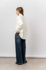 Sweater de tejido de punto color beige, con cuello alto, hombros caídos, mangas largas con puños acanalados y tajos laterales en el ruedo.