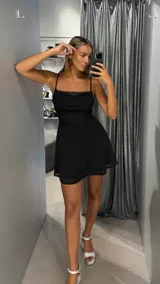 Vestido corto negro con destellos brillantes, diseño de tirantes finos y escote drapeado tipo cowl.