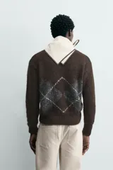 Jersey de punto marrón oscuro con diseño jacquard de rombos en gris y blanco, cuello redondo y manga larga.