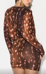 Vestido corto de malla transparente con estampado tie-dye en tonos marrones y rosados. Presenta escote pronunciado en V con efecto drapeado y mangas largas ajustadas.