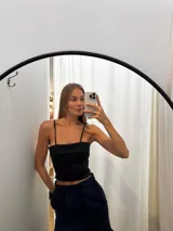 Top negro de tirantes finos con diseño de capas horizontales y corte recto. Confeccionado en tafeta, presenta un estilo versátil y minimalista.