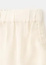 Short mini de viscosa semitransparente color crudo, con diseño bordado, bajo festoneado y cintura ajustable con elástico en los laterales.