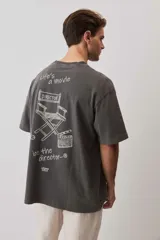 Remera marrón oversize de manga corta, con cuello redondo y pequeño estampado gráfico en el pecho.