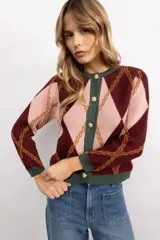 Cardigan de punto con patrón argyle en tonos bordó y rosado, con detalles en color verde oscuro en los bordes, puños y cuello. Presenta cierre frontal con botones dorados y diseño de ajuste clásico.