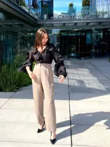 Blusa negra traslúcida con escote en V y volados en el frente y mangas largas abullonadas.