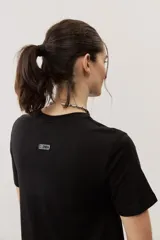 Vestido midi negro con diseño de manga corta, cuello redondo y bolsillos laterales, corte amplio y fluido.